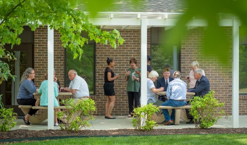 A group of people are sitting at picnic tables on a porch.