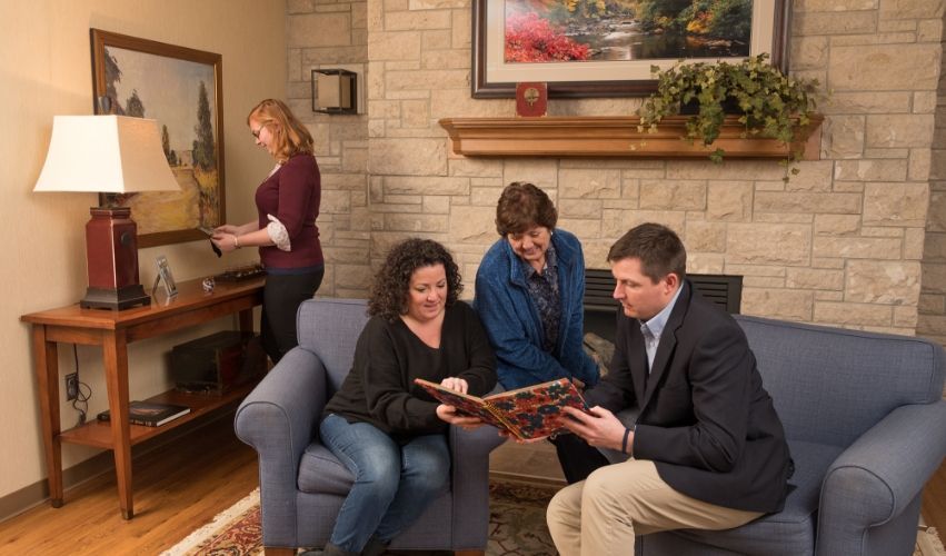 A group of people are sitting on a couch looking at a book.