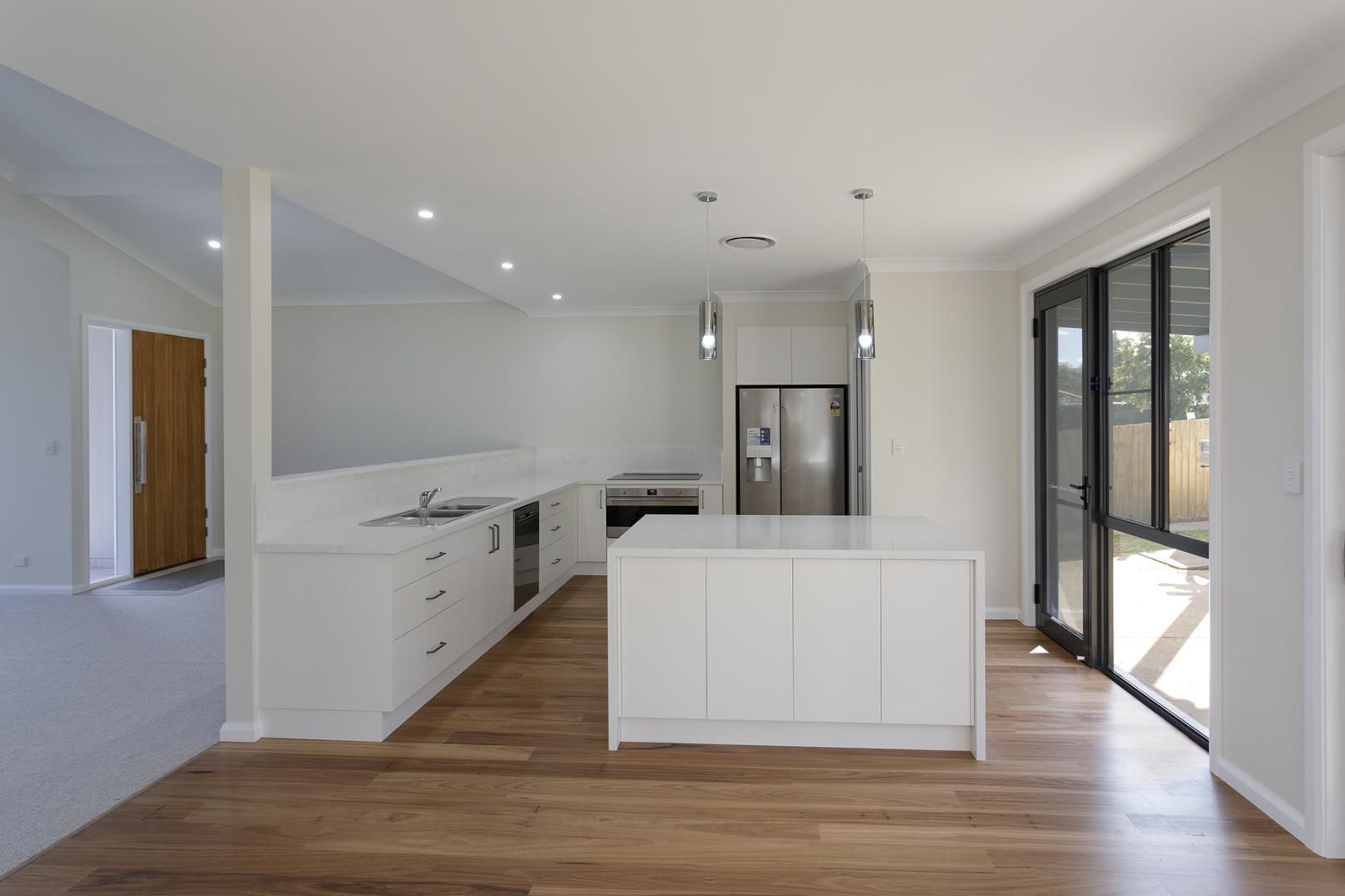 An Empty Kitchen With White Cabinets and Hardwood Floors — Kareela Constructions In Tamworth, NSW