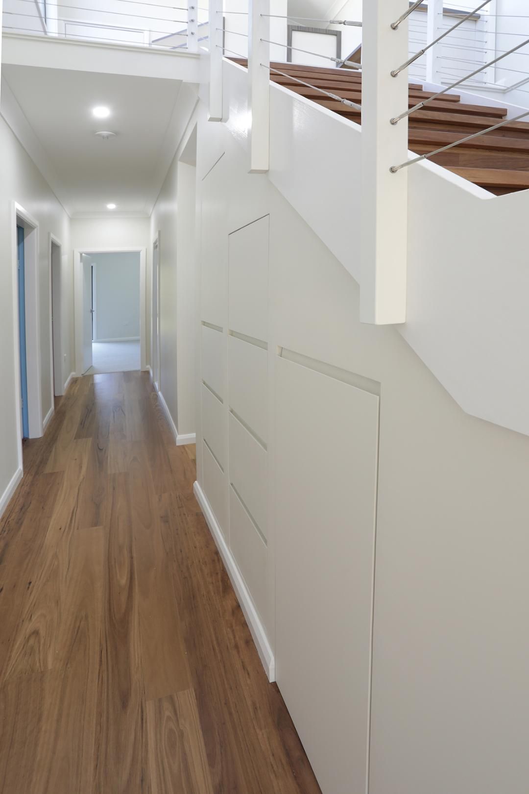 A Long Hallway With Wooden Floors and White Walls Leading to a Staircase — Kareela Constructions In Tamworth, NSW
