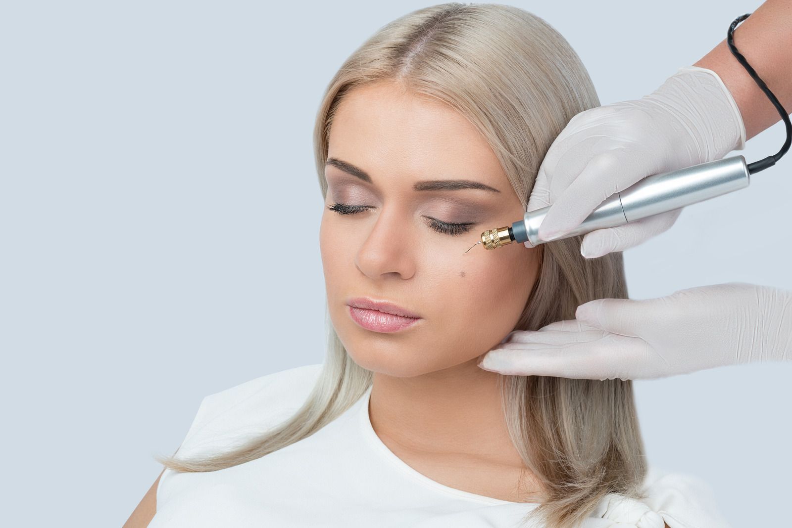 A woman is getting a treatment on her face.