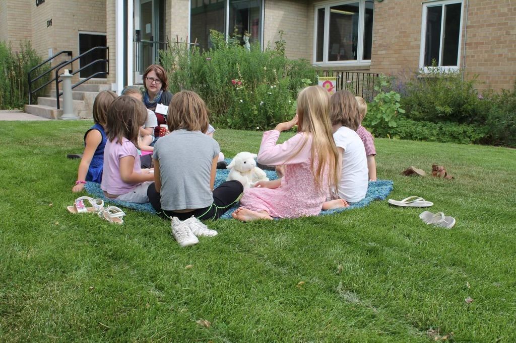 group of chlldren sitting on the grass in front of a building