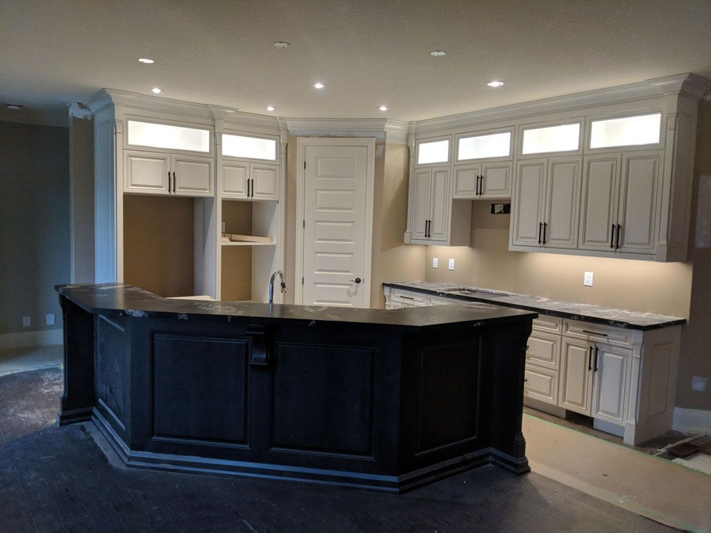 Residential Electrical Contractor - A kitchen with white cabinets and a black island