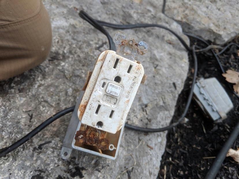 Residential Electrical Contractor - A close up of a rusty electrical outlet on the ground