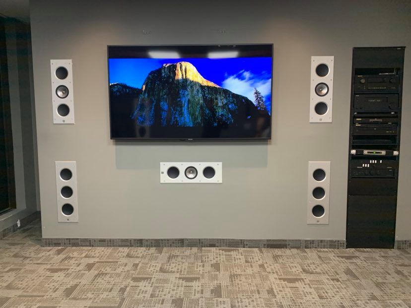 Residential Electrical Contractor - A large flat screen tv is mounted on a wall with speakers.