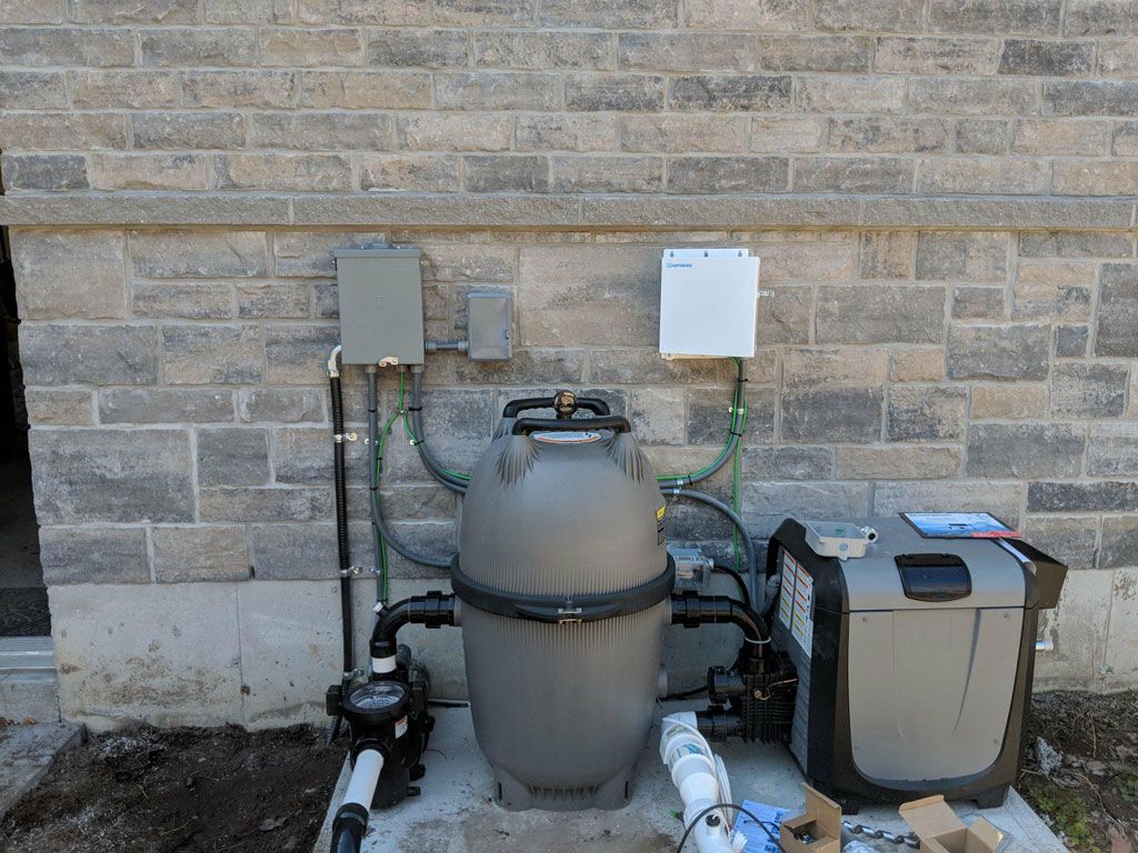 Residential Electrical Contractor - A swimming pool filter is sitting on the side of a brick building.