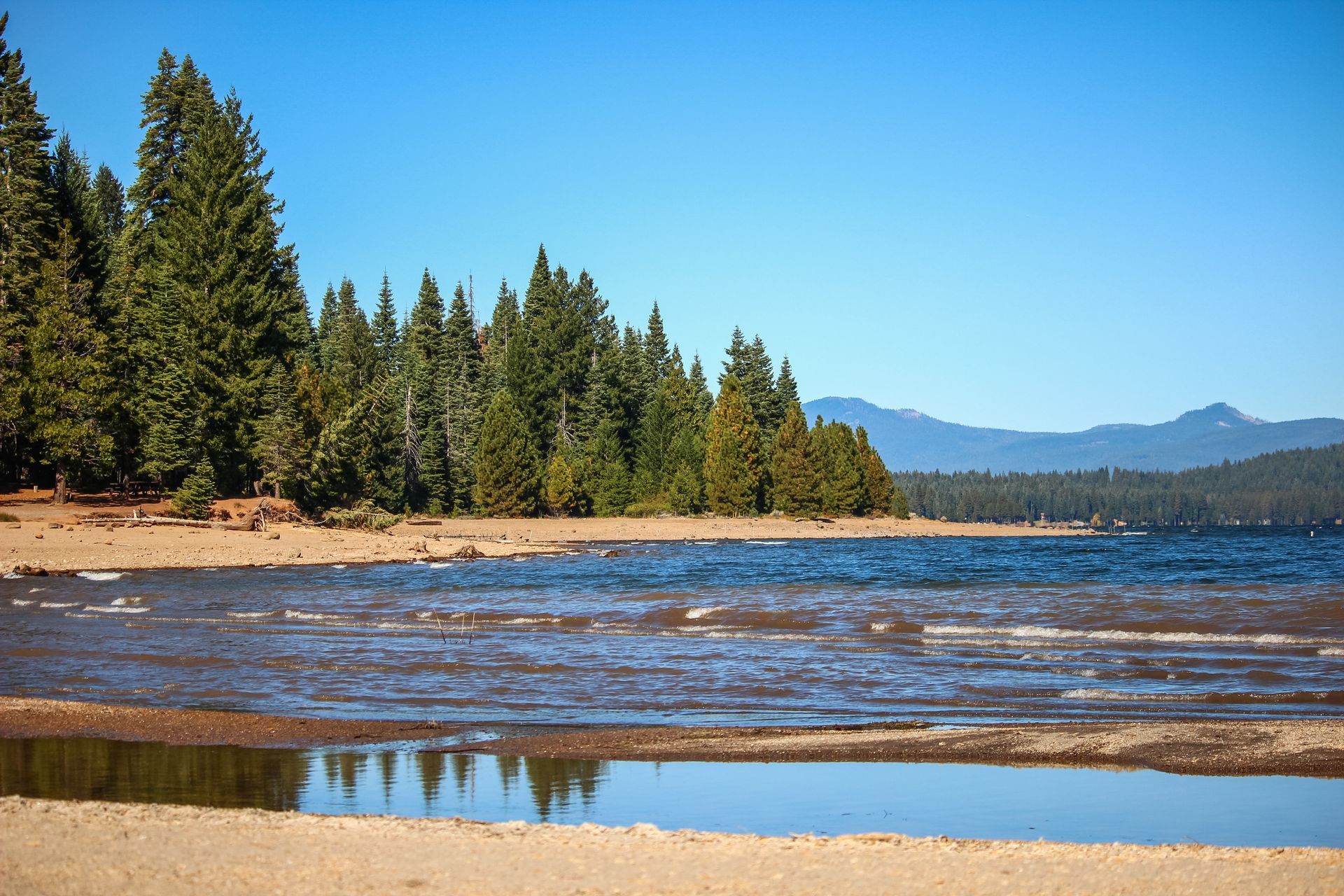 A lake with trees on the shore and mountains in the background