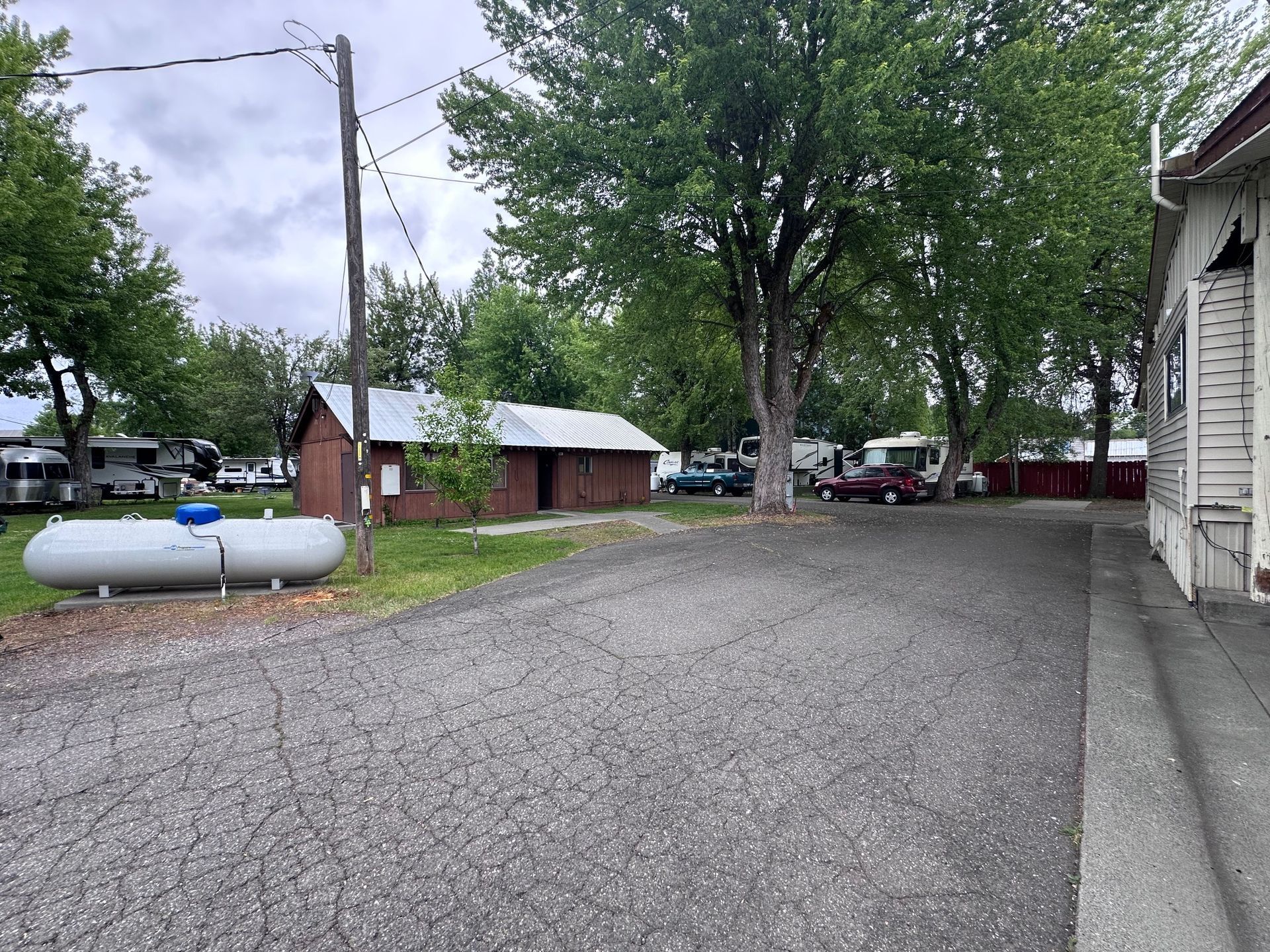 A propane tank is sitting on the side of a gravel road.