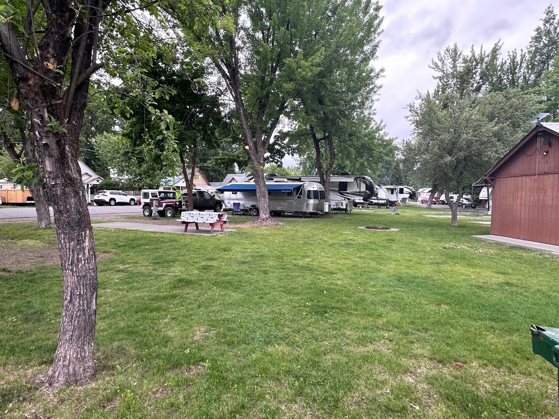 A rv park with a picnic table in the middle of the grass.