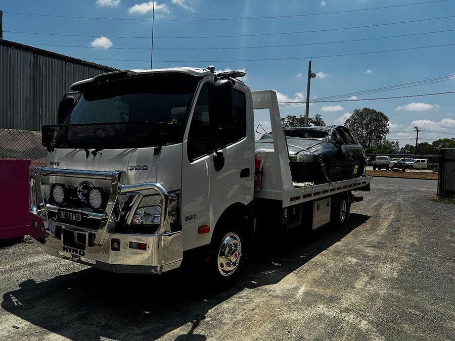 A Tow Truck With a Car on the Back is Parked in a Parking Lot — Tow Biz in Park Avenue, QLD