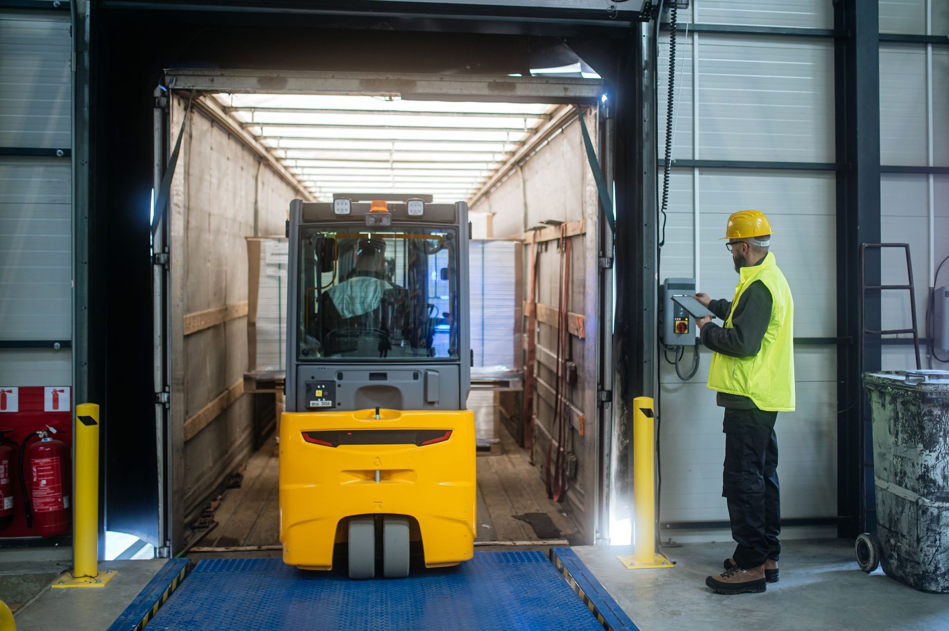 Person in blue work suit and white gloves working on orange machinery.