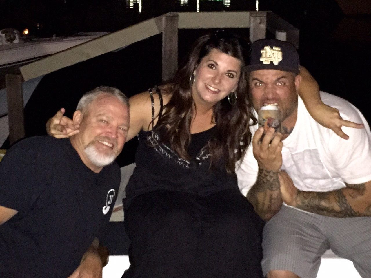 Three people smiling together at night; man on right holding ice cream.