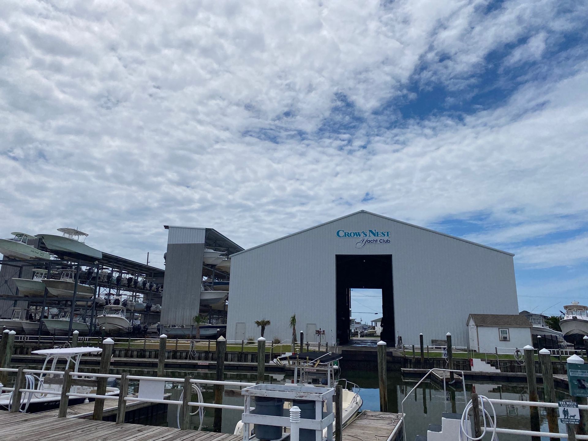 Dry storage facility for boats at a marina under a bright, cloudy sky.