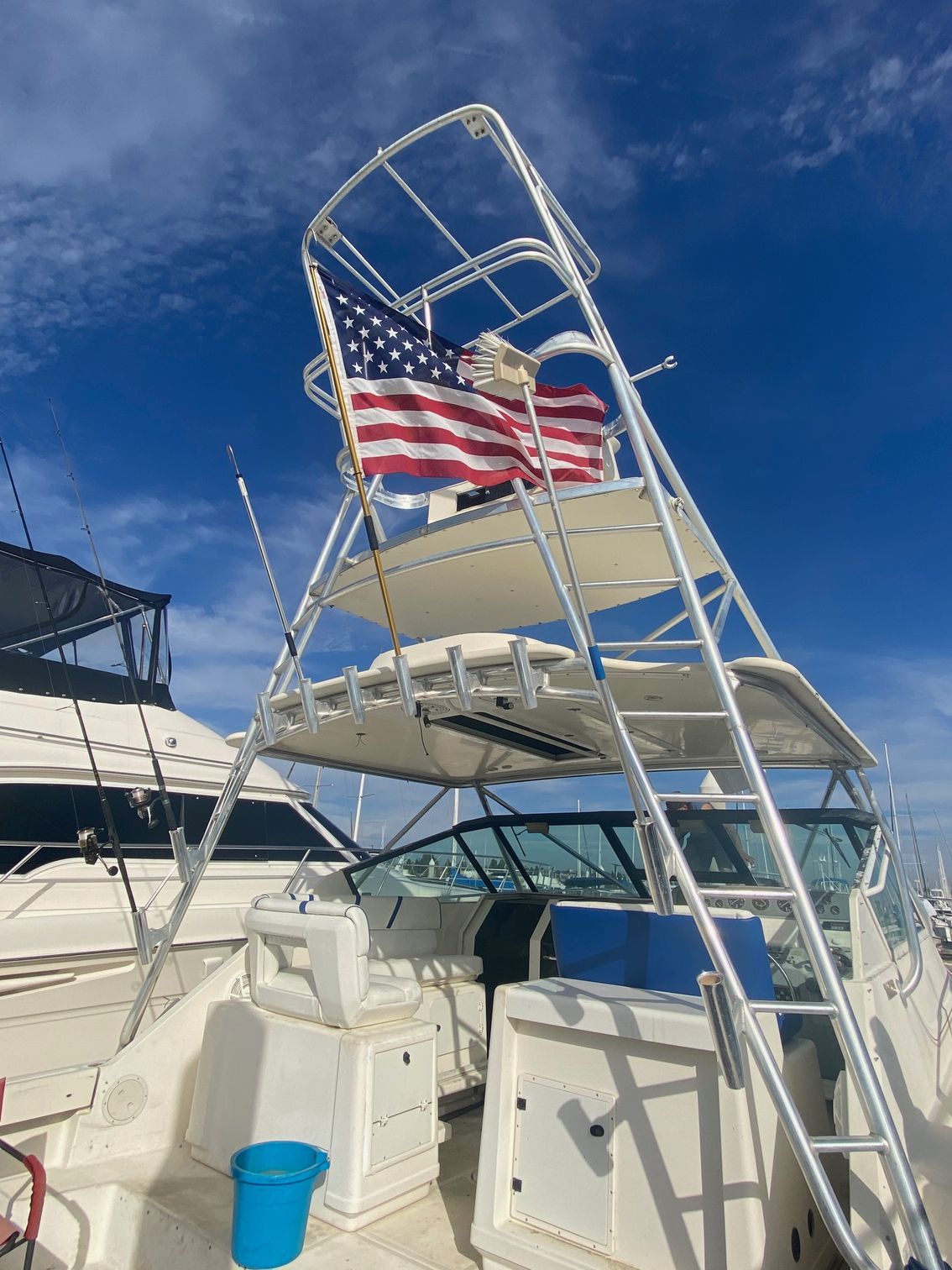 An American flag flies on a metal tower structure aboard a white boat docked on a sunny day.