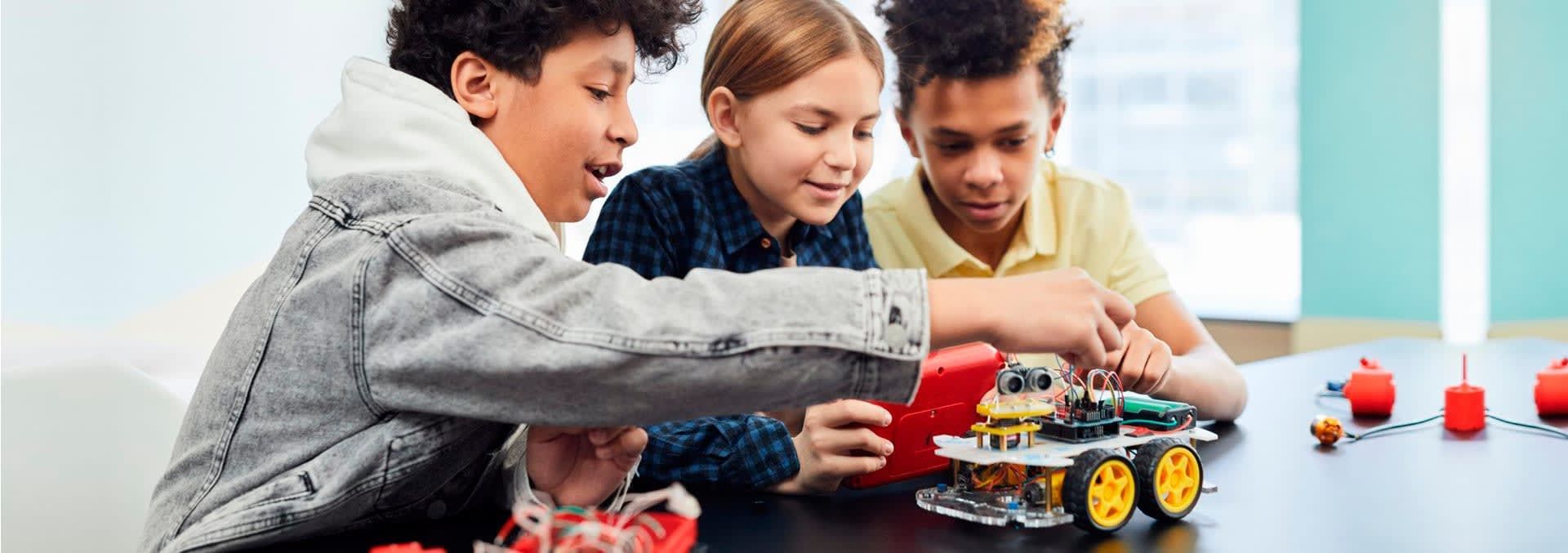 Three children working on a LEGO robot at a table, focused and engaged.
