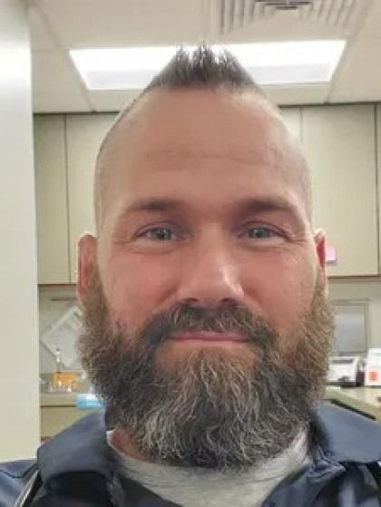 A man with a beard and mohawk is smiling for the camera.