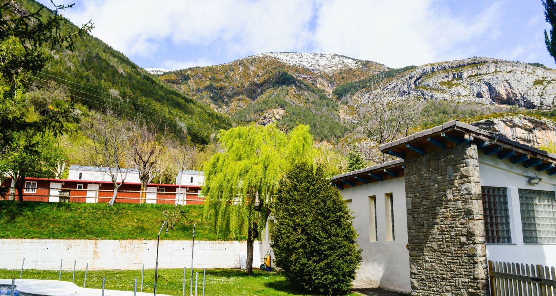 There is a house in the middle of a field with mountains in the background.