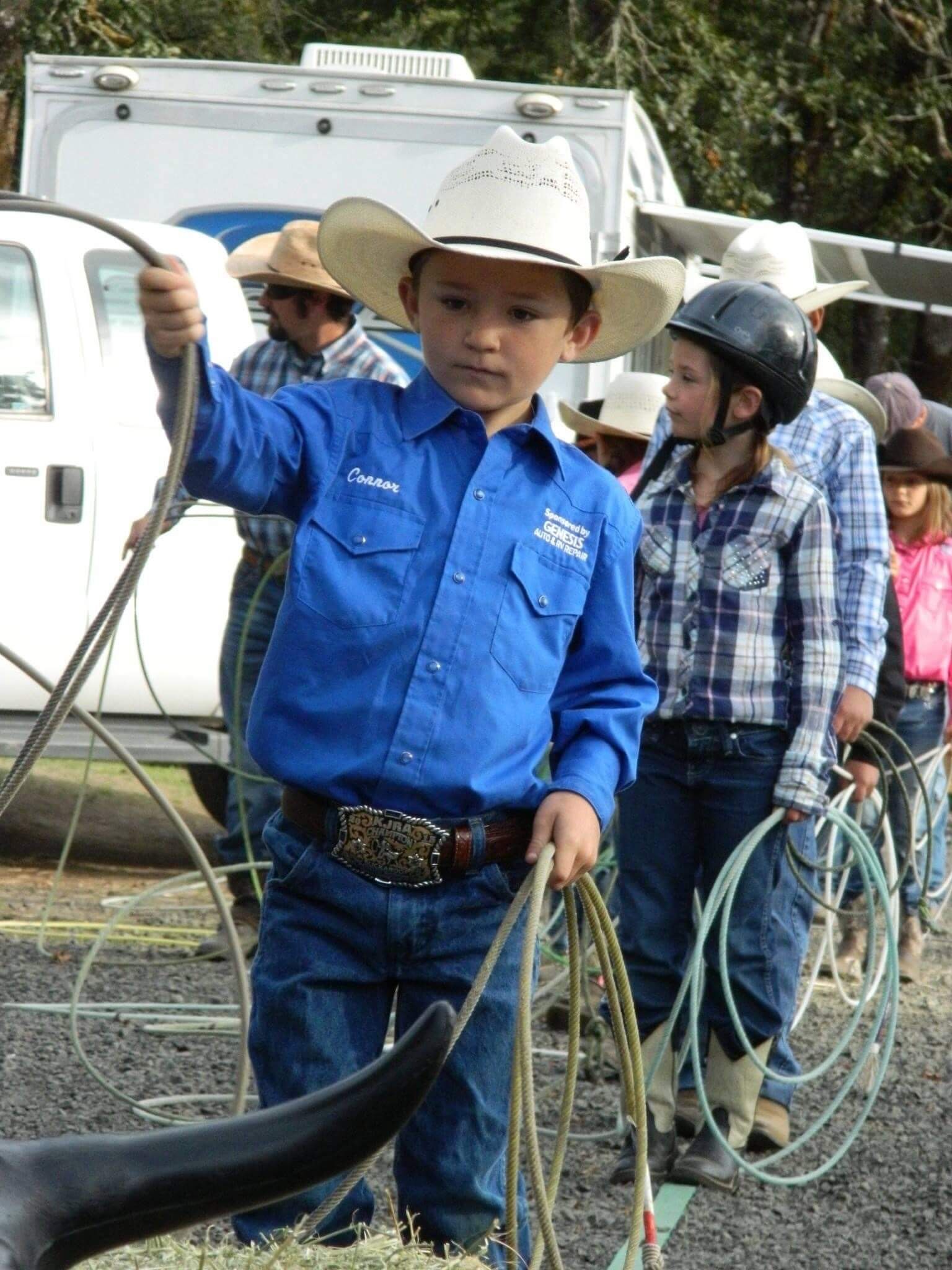 Boy in blue shirt and cowboy hat practices roping, outdoors | Genesis Automotive and RV Repair