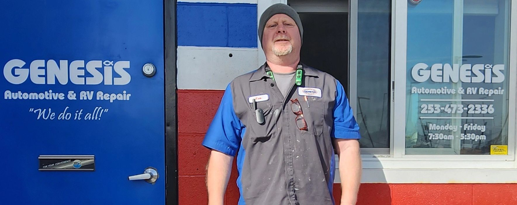 Man in gray and blue uniform stands outside "Genesis Automotive & RV Repair" building | Genesis Automotive and RV Repair