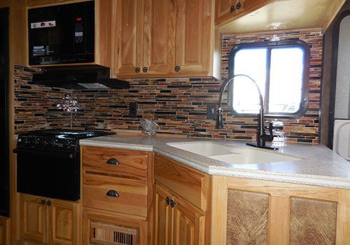 RV kitchen with light wood cabinets, stove, and a decorative tile backsplash | Genesis Automotive and RV Repair
