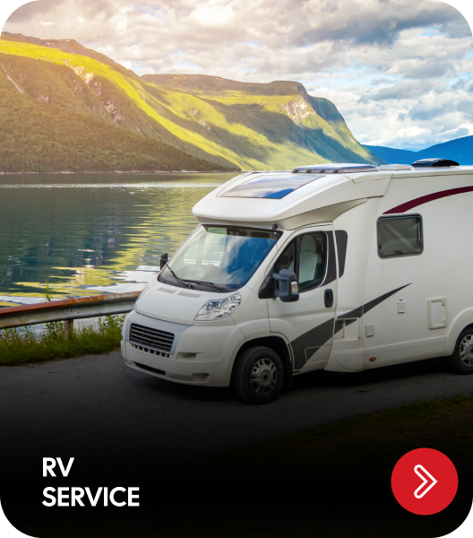 RV parked on a road by a lake and mountains; 