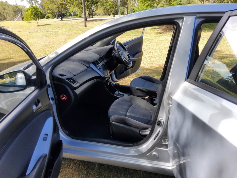 A Silver Car With The Door Open Is Parked In A Grassy Field — N & R Automotive Group in Bundaberg East, QLD
