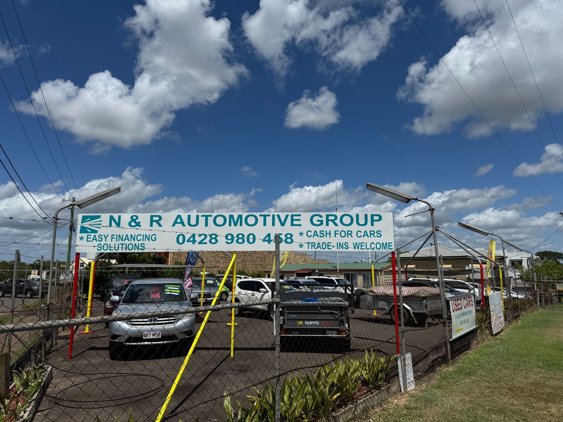 A Business Sign is Displayed Above Some Cars in a Car Yard.— N & R Automotive Group in Bundaberg East, QLD