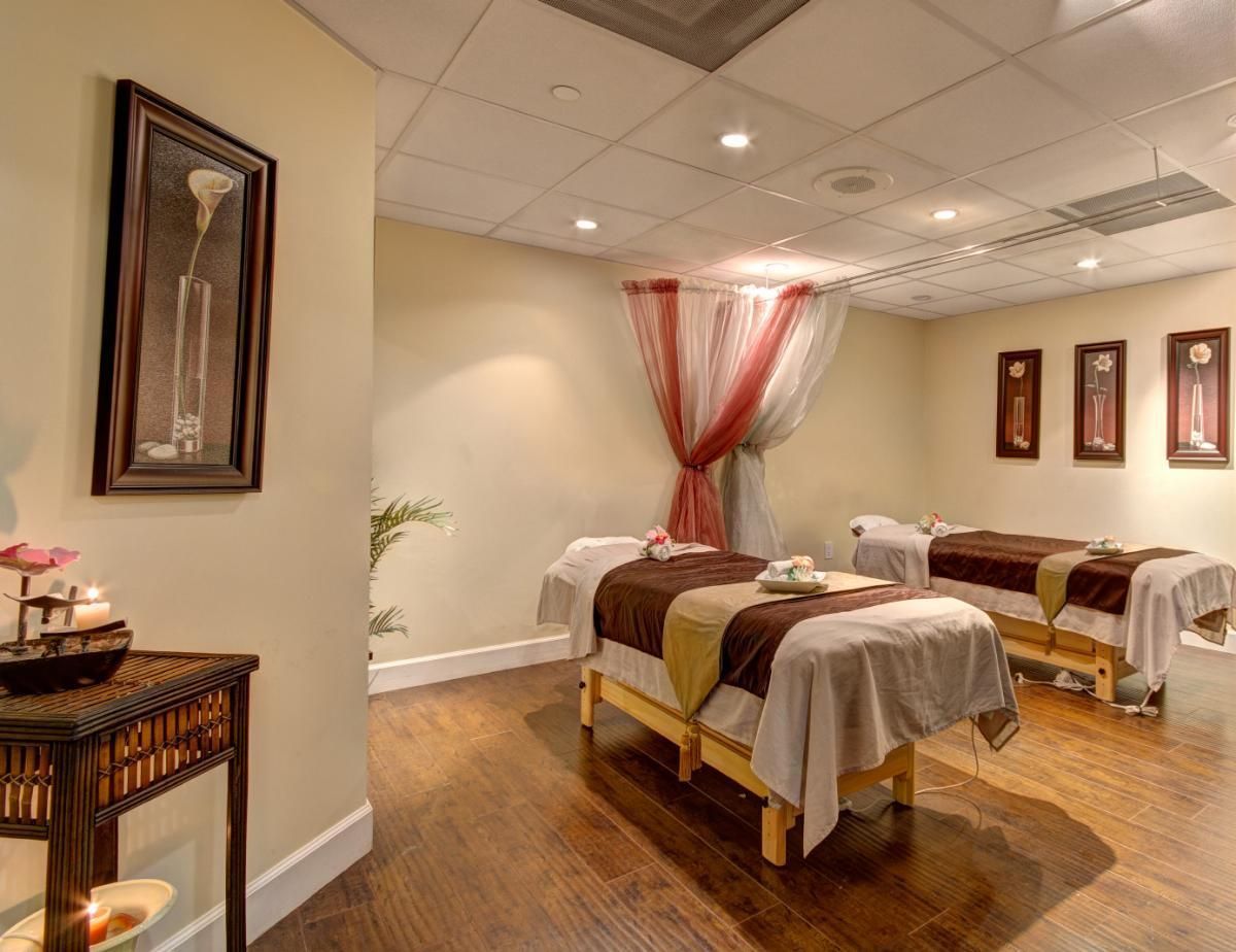 There are two massage tables in a room with wooden floors.