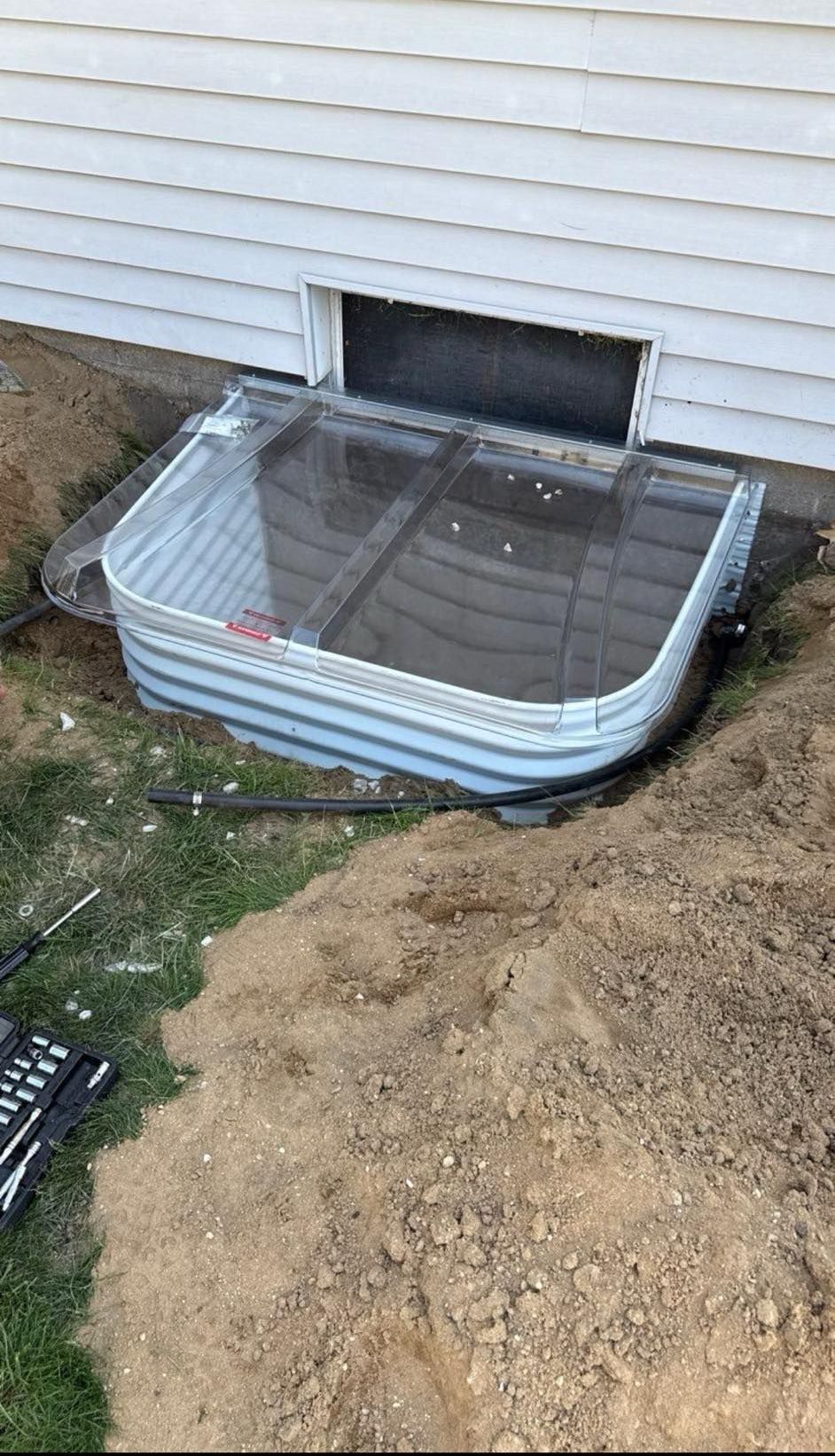 A window well is being installed in the basement of a house.
