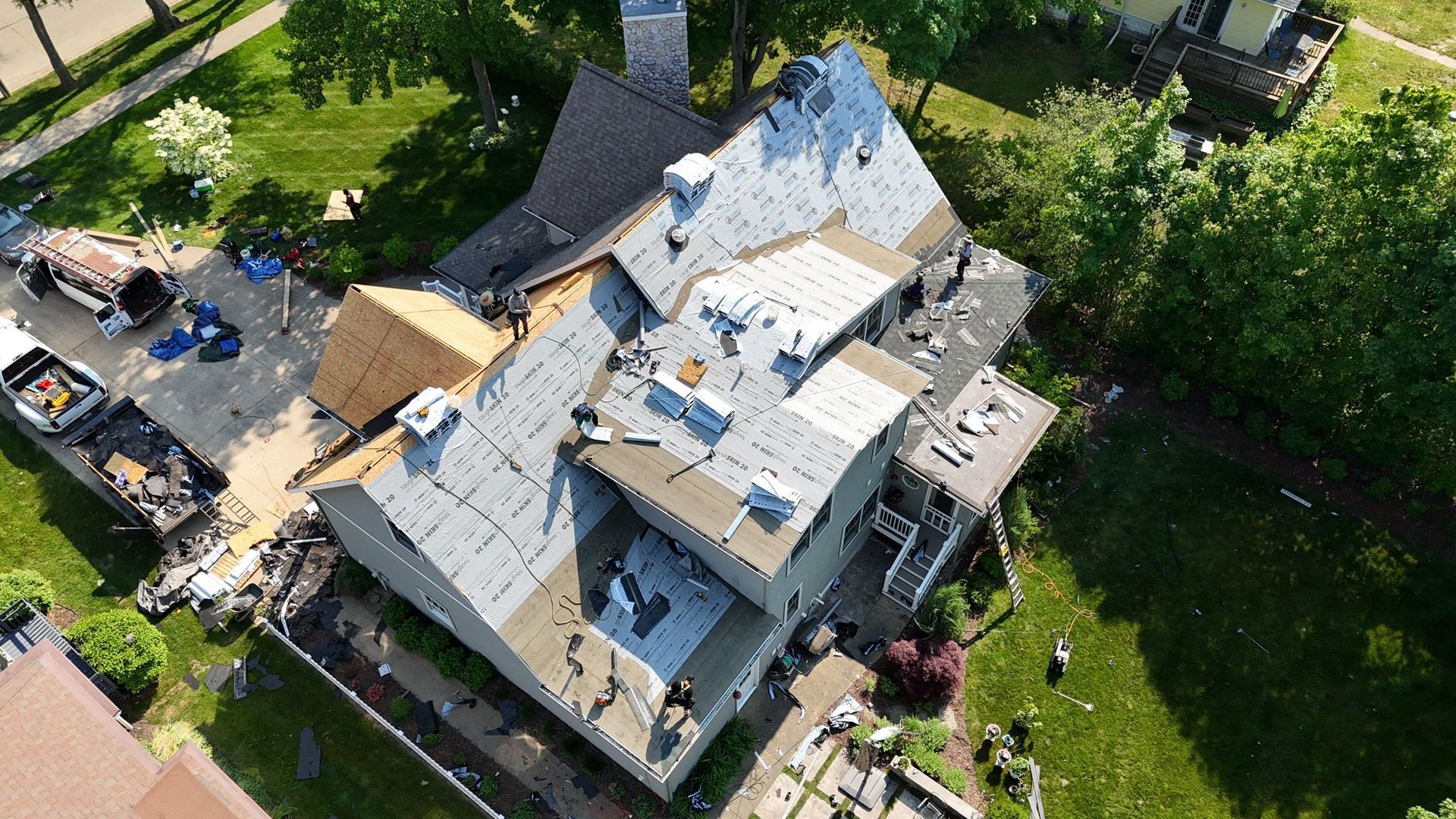 An aerial view of a house under construction with a roof being installed.