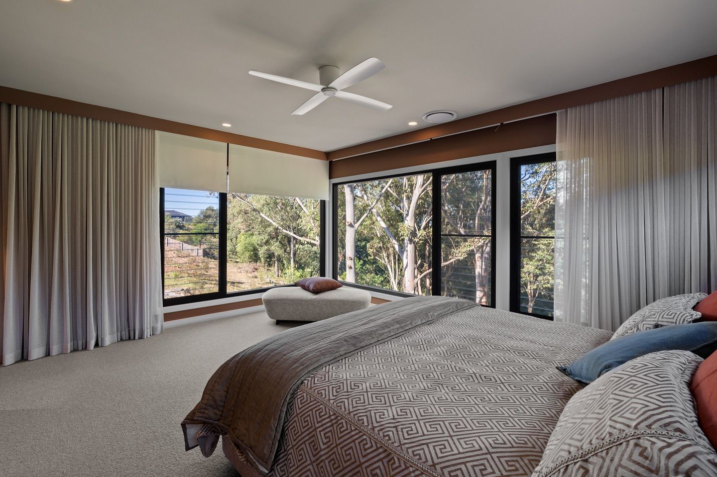Bedroom with large windows, light curtains, and bed facing the window, overlooking a lush forest. — Glenn Koek - Shutters - Curtains - Blinds in West Wollongong, NSW
