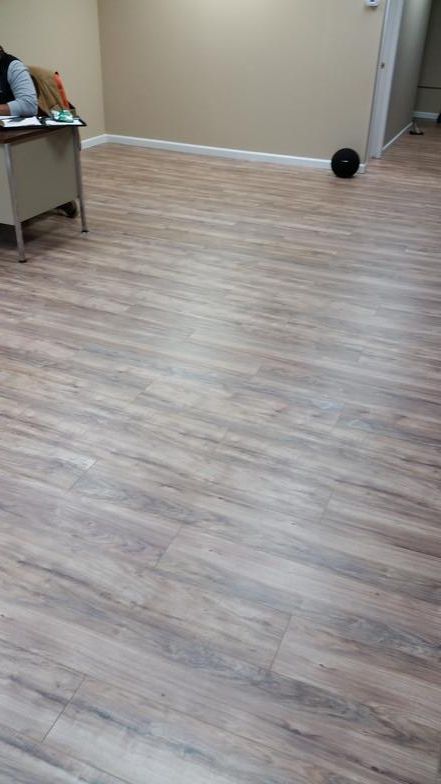 A person is sitting at a desk in a room with a wooden floor.