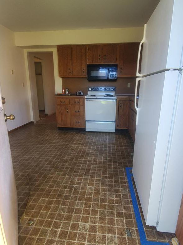 A kitchen with a stove , refrigerator , microwave and cabinets