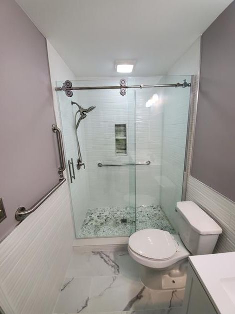 A bathroom with a toilet , sink , shower and sliding glass door.