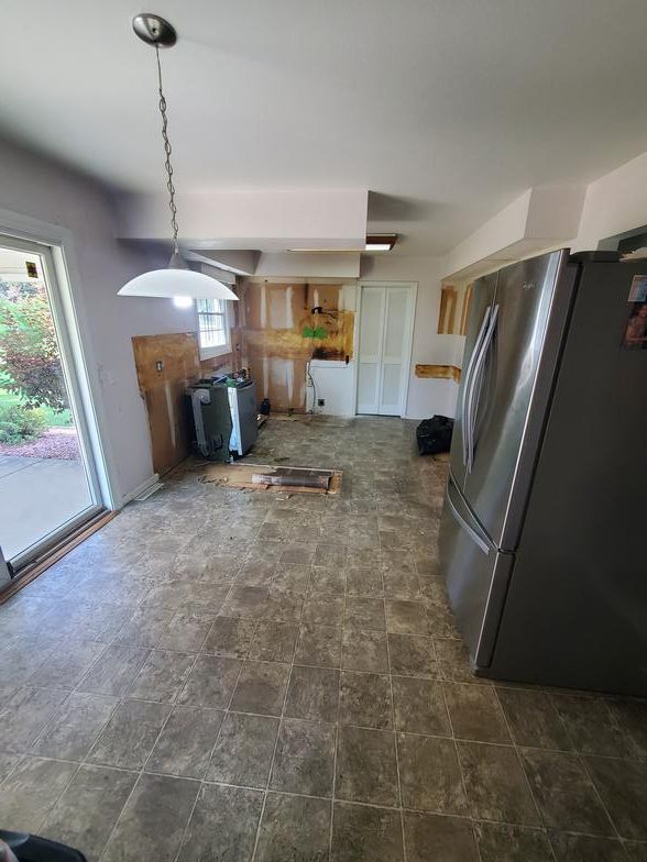 A kitchen with a stainless steel refrigerator and a sliding glass door.