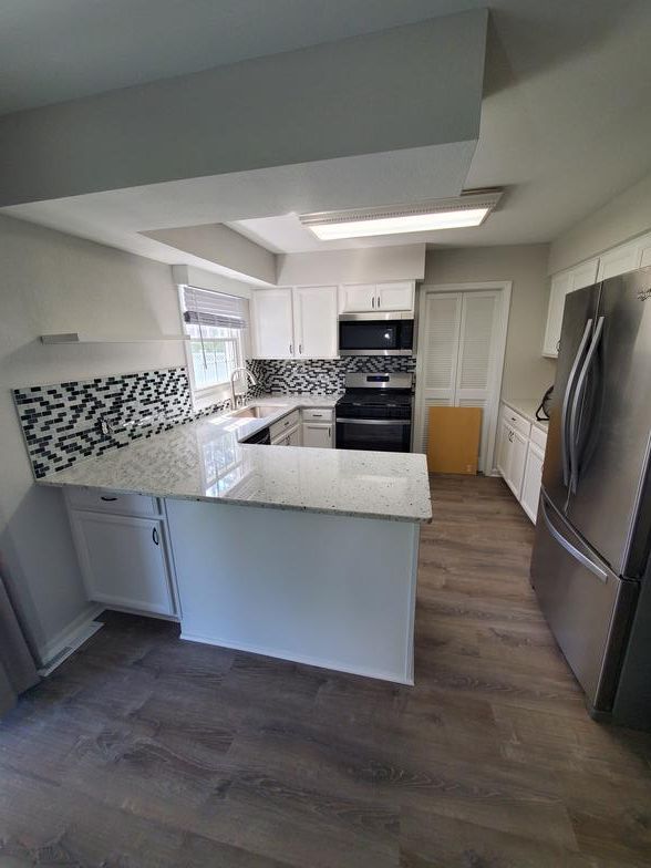 A kitchen with stainless steel appliances and white cabinets.