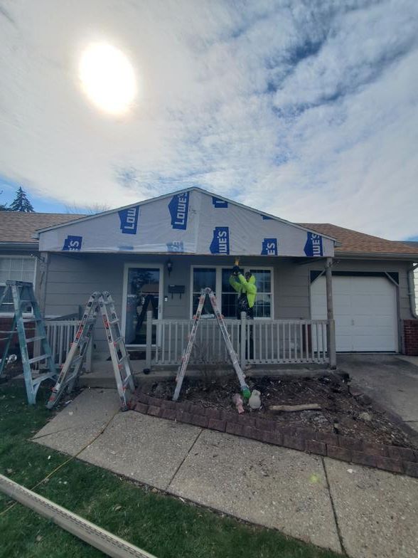A man is standing on a ladder in front of a house.
