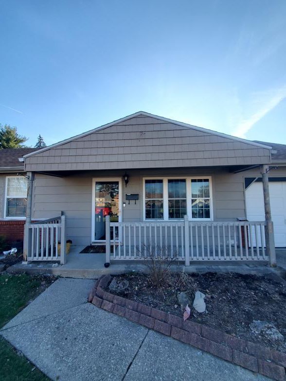The front of a house with a porch and a fence.