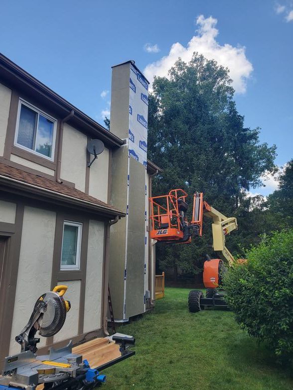 A large chimney is being installed on the side of a house.