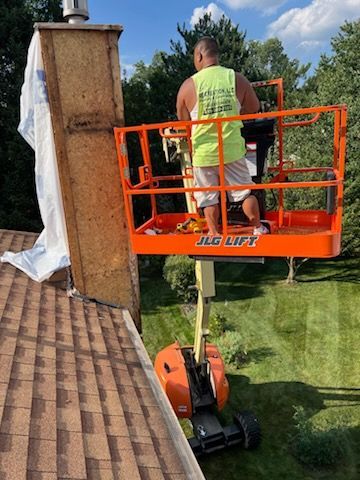 A man is sitting on a lift on top of a roof.