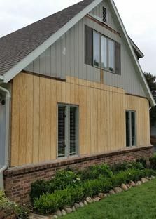 A house with a wooden siding and shutters on the windows.