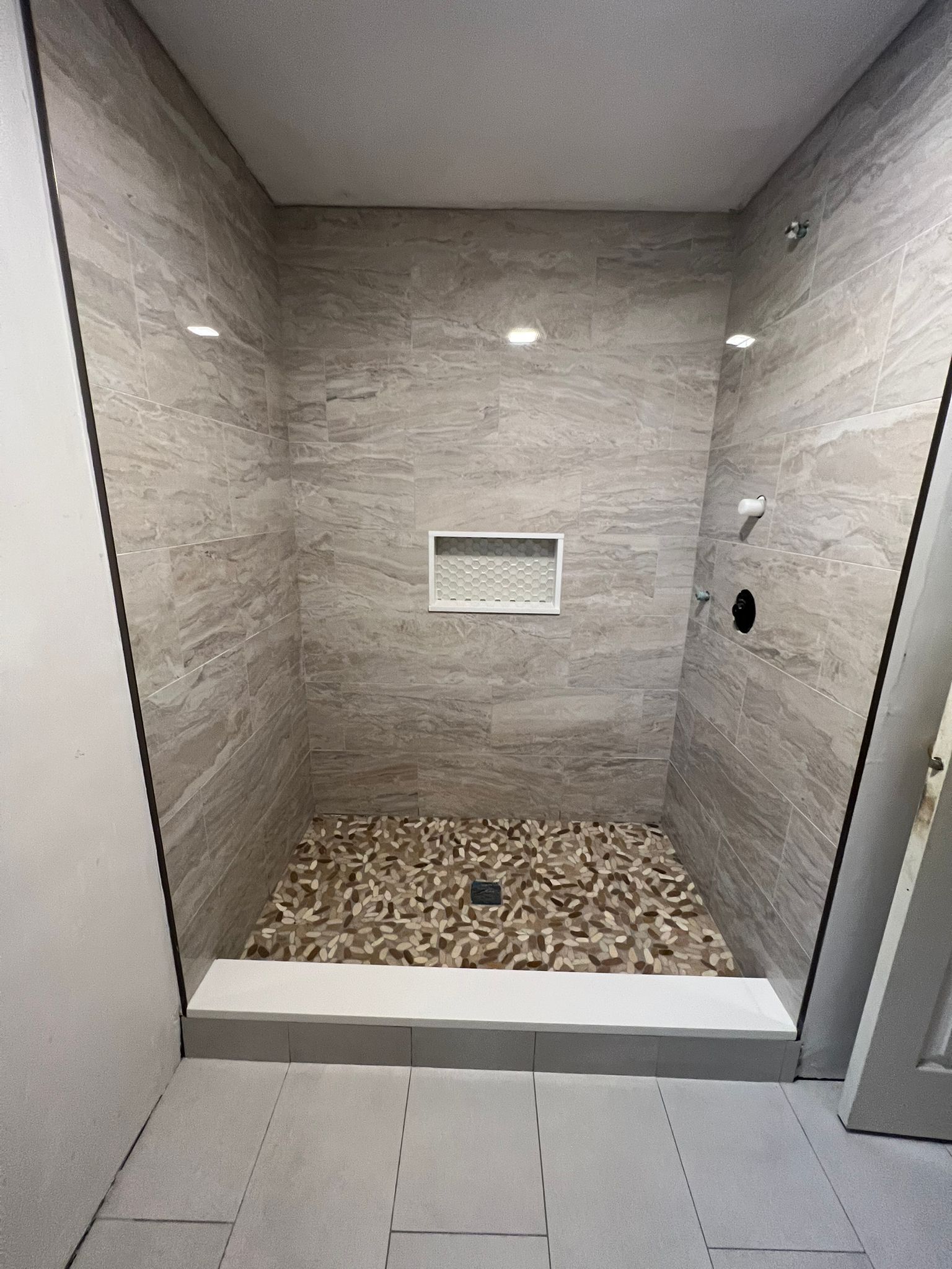 a walk in shower with a tiled floor and a glass door - after services with American Bath Wroks