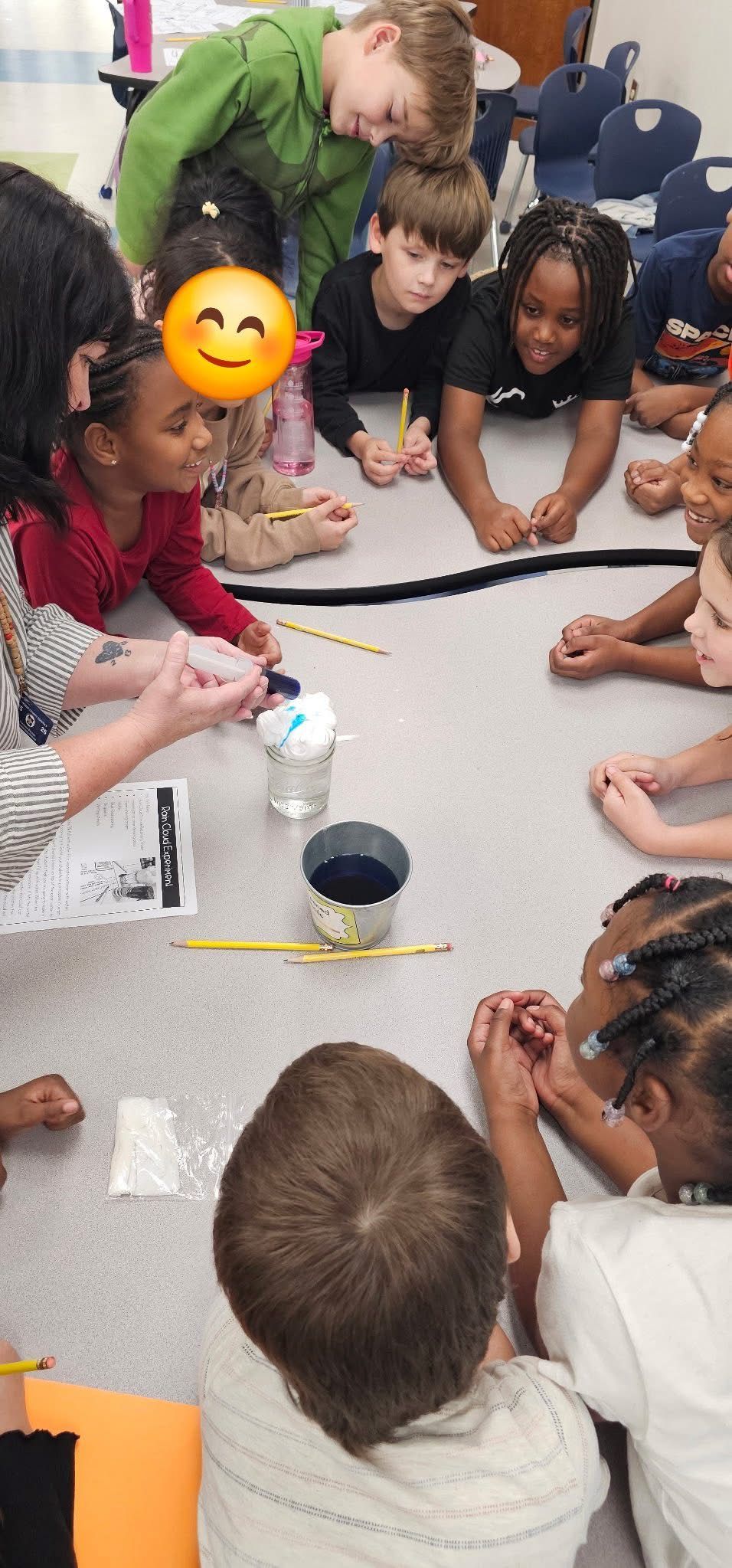A diverse group of children gathers around an instructor to watch a science demonstration