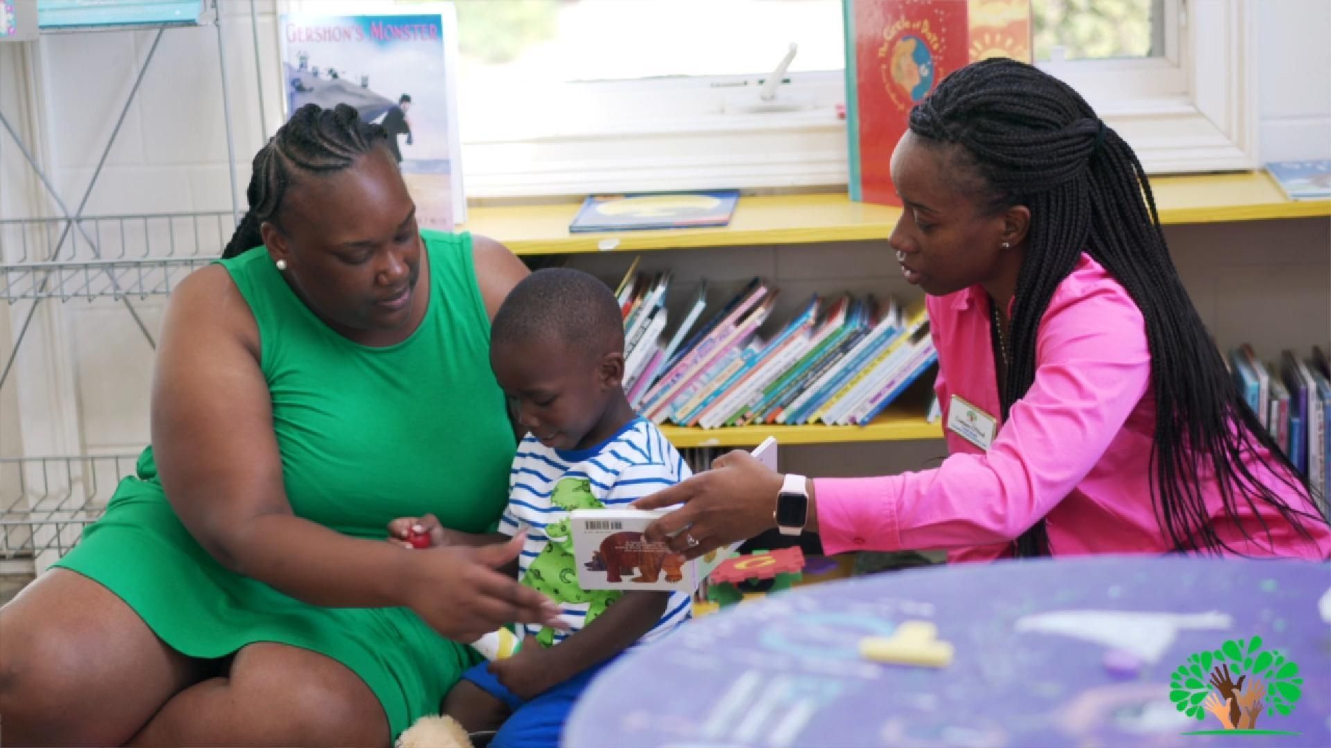 Children and adults working on computers in a computer lab. Some children have headphones