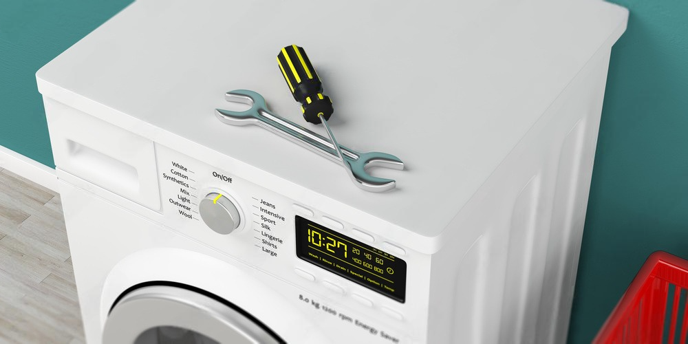 A wrench and screwdriver are sitting on top of a washing machine.