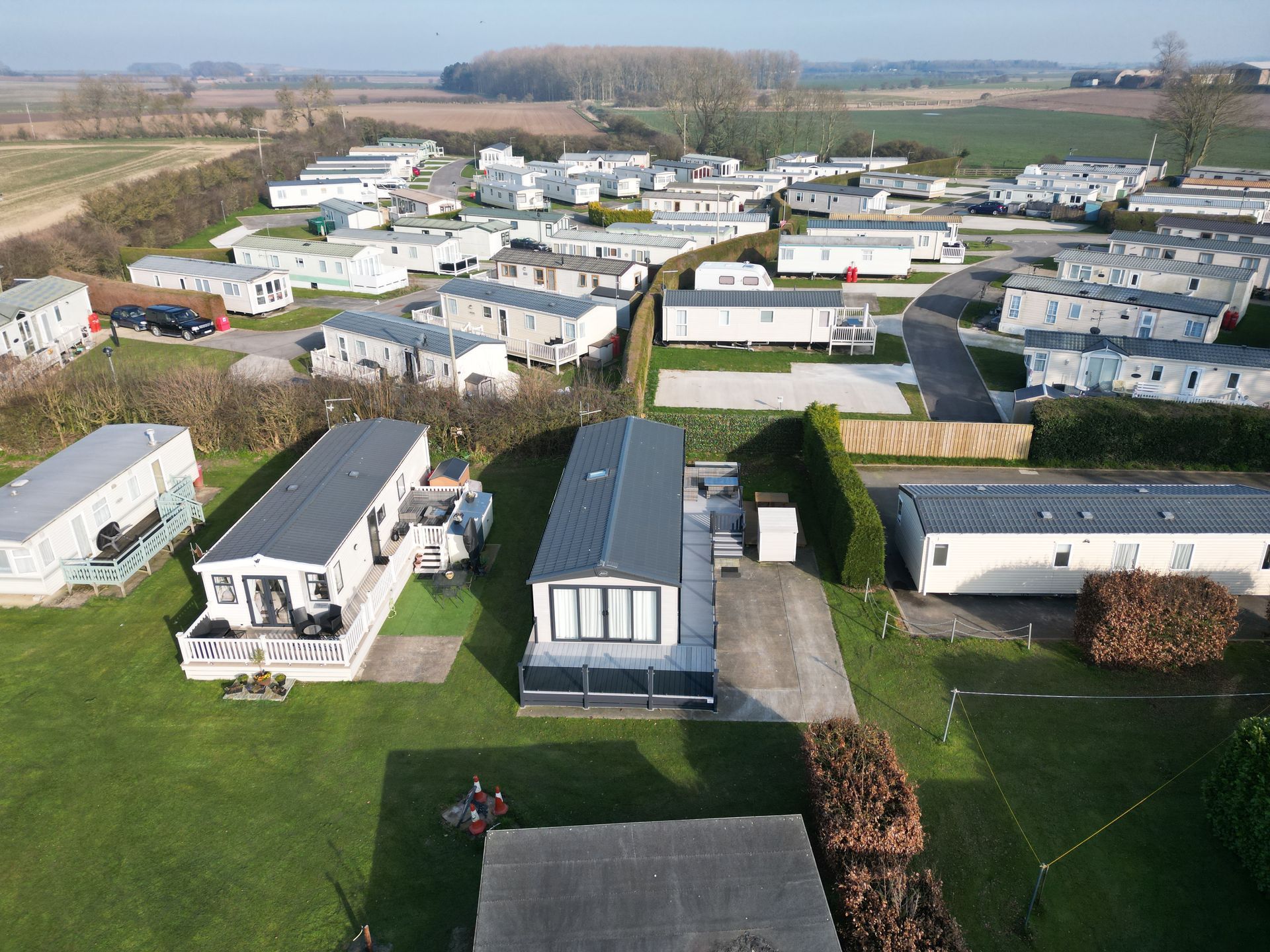 Aerial view of a caravan park with rows of mobile homes and green spaces under a bright sky.