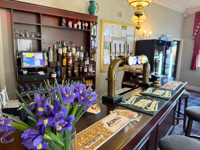A bar with a vase of purple flowers on it