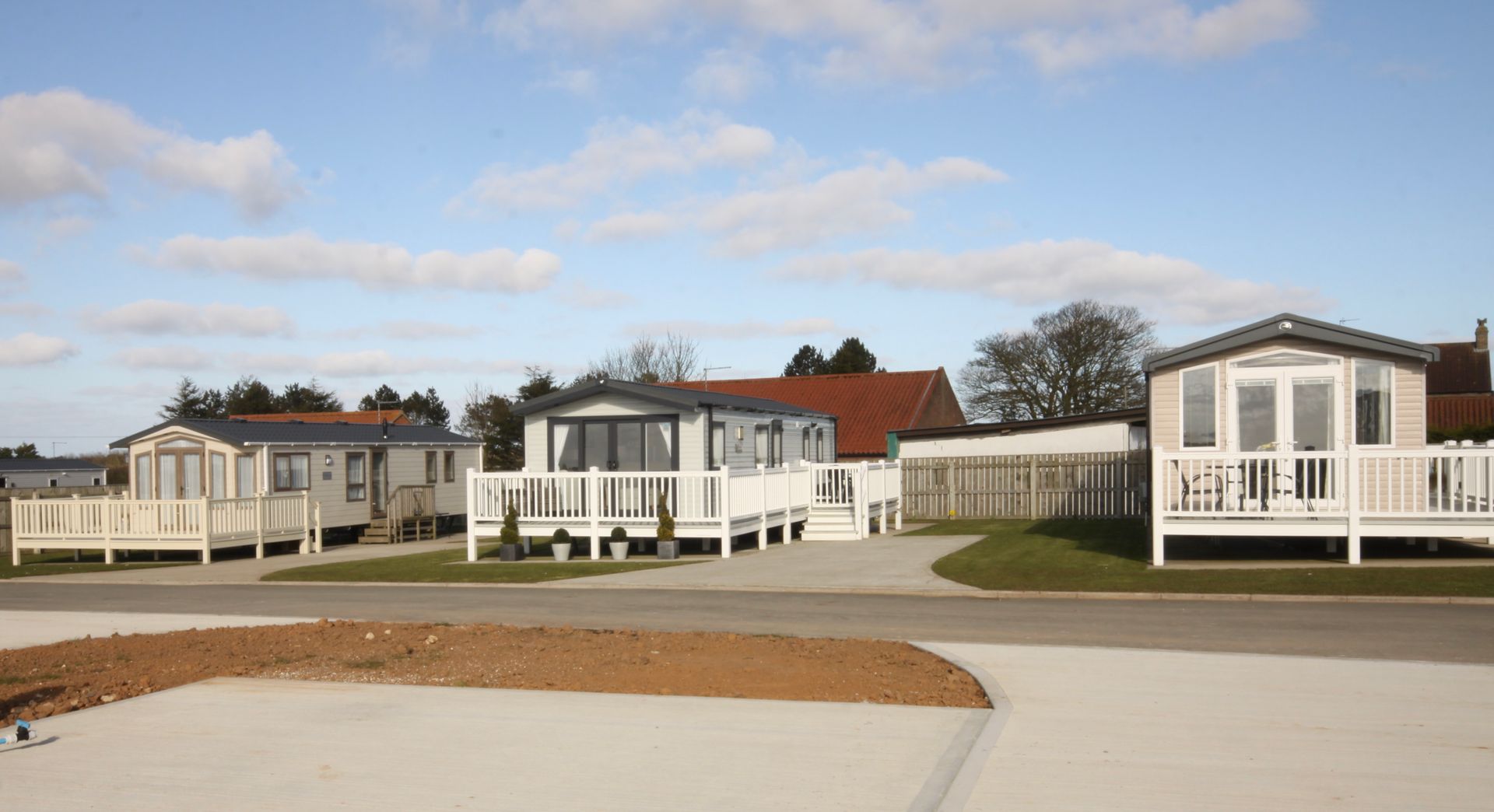 Caravan park with white static caravans on a paved area under a blue sky.