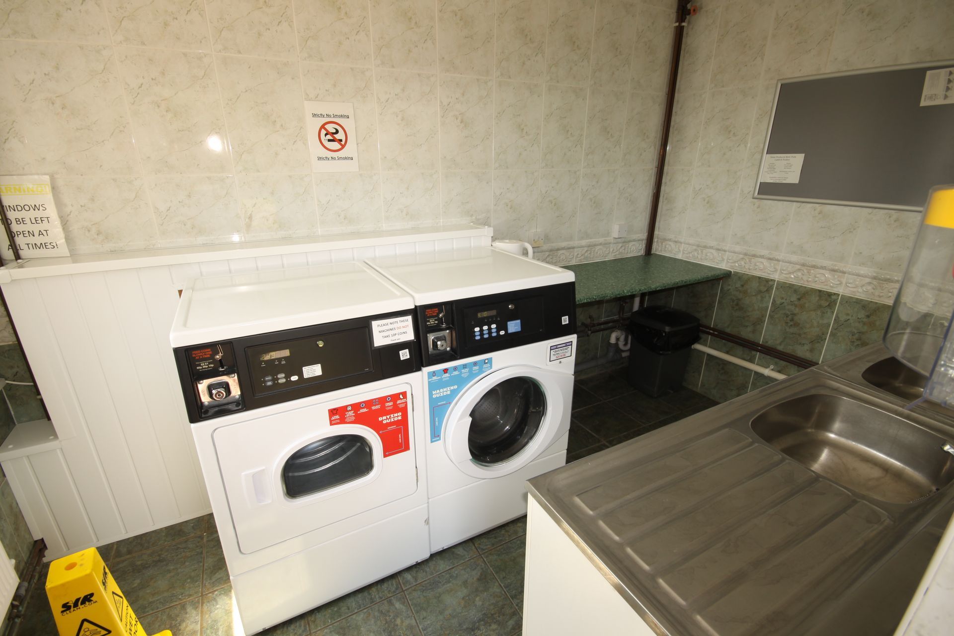Laundry room with washing machines, sink, and a no-smoking sign.