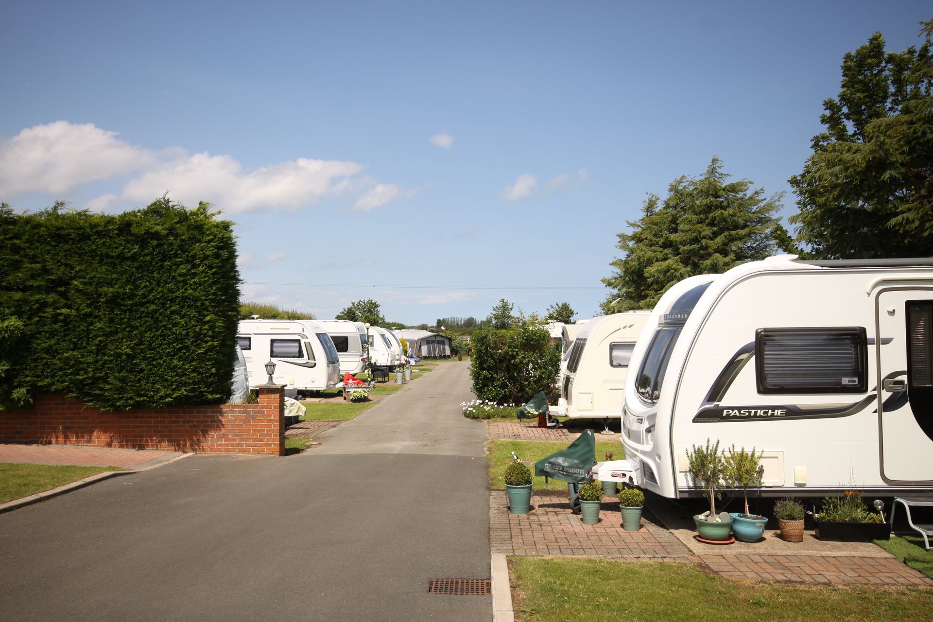 Caravan park with several white caravans parked along a paved road under a blue sky.